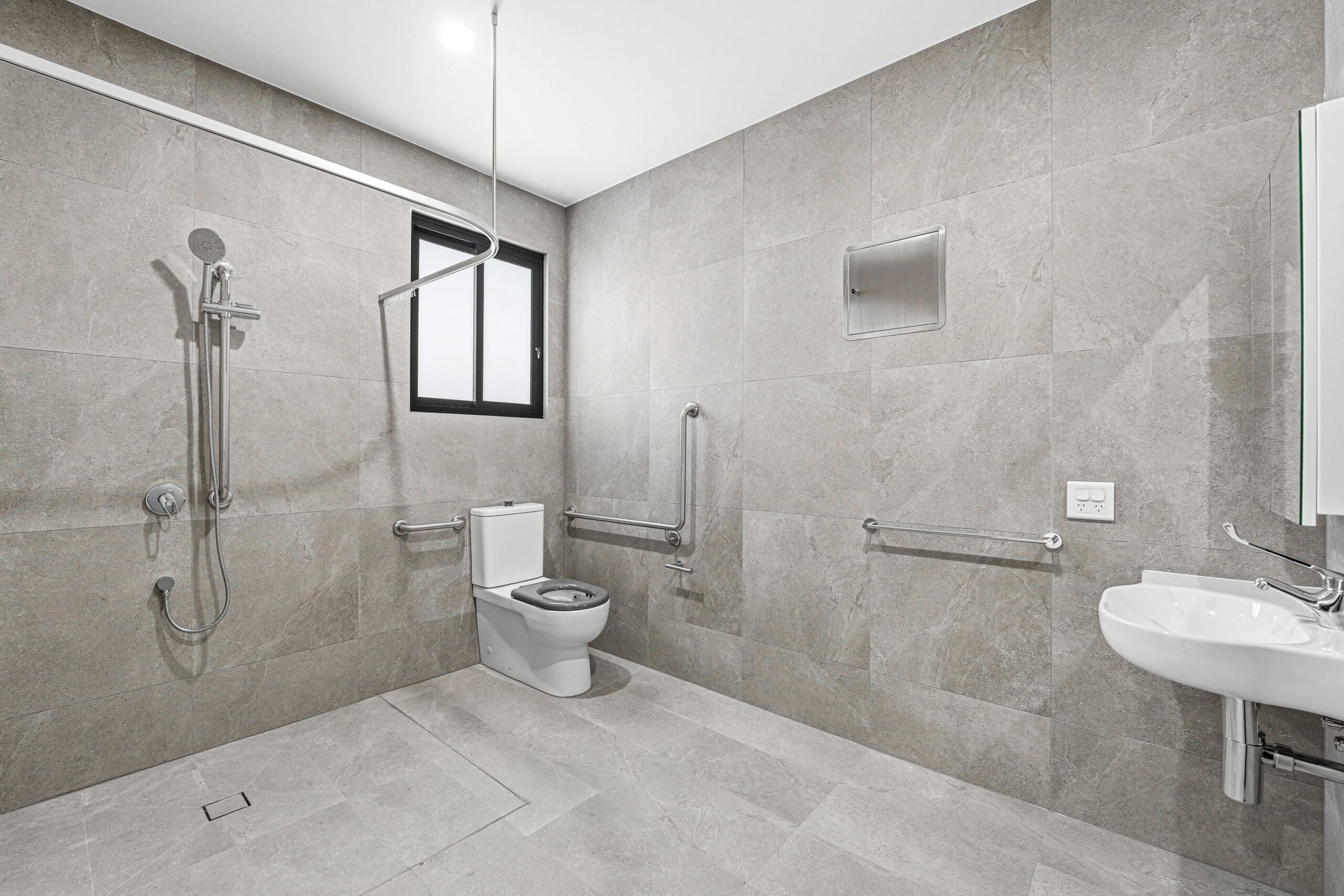 Accessible bathroom with roll-in shower and grab rails at the Beyond Care Auburn SDA home