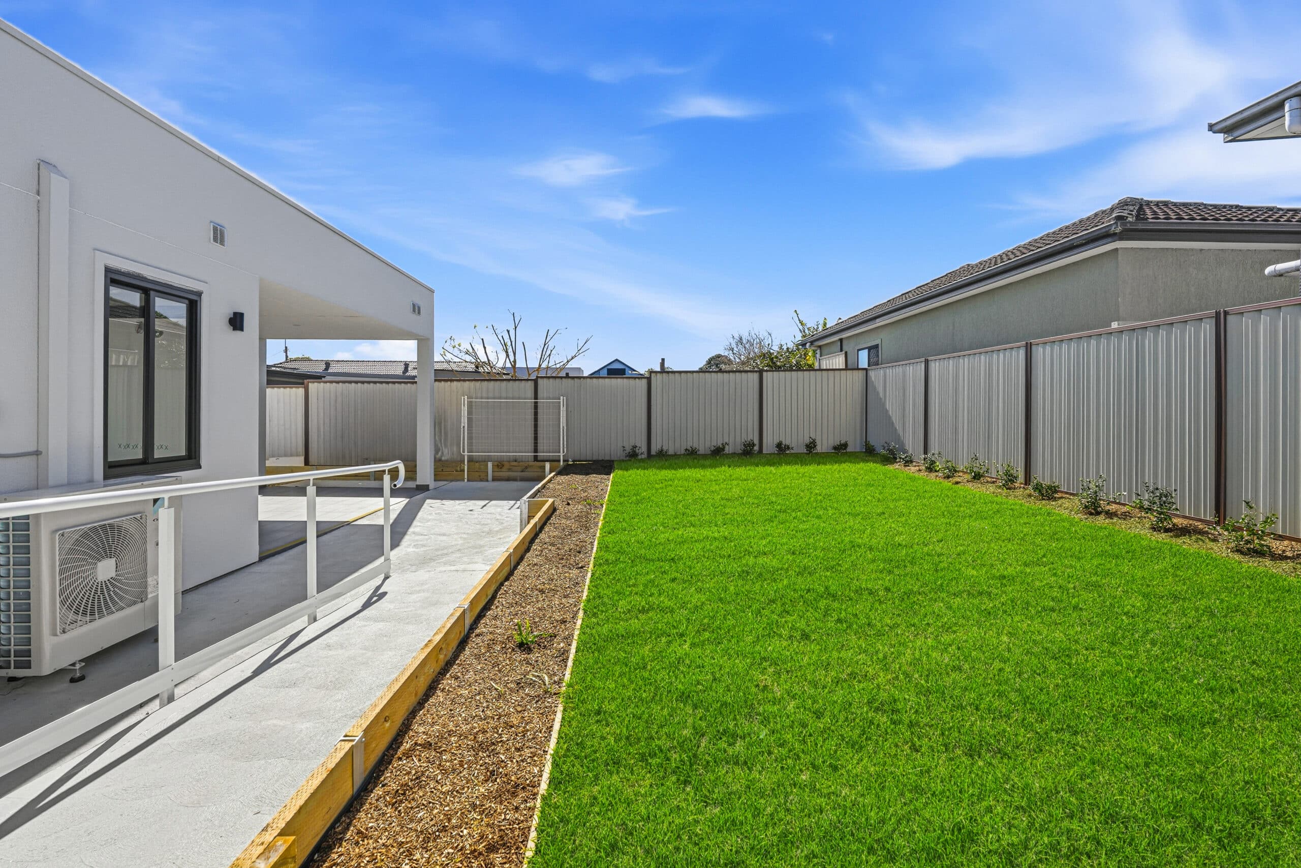Landscaped backyard with lawn and outdoor entertaining area at the Beyond Care Auburn SDA home
