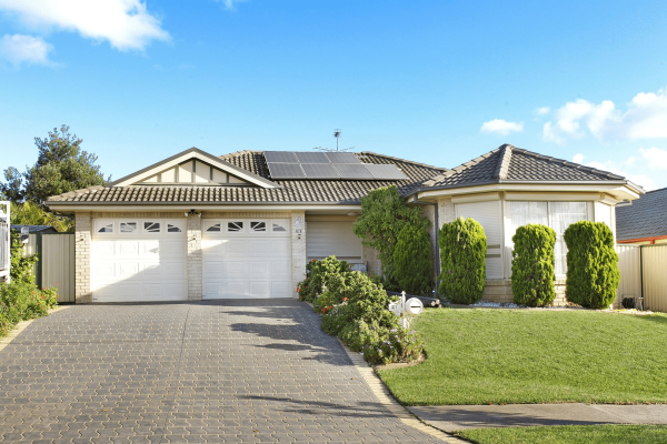 Liverpool 1 Single-story suburban house with two-car garage, solar panels, well-maintained lawn, and paved driveway under a blue sky—ideal SIL Accommodation in Sydney for comfortable supported independent living.
