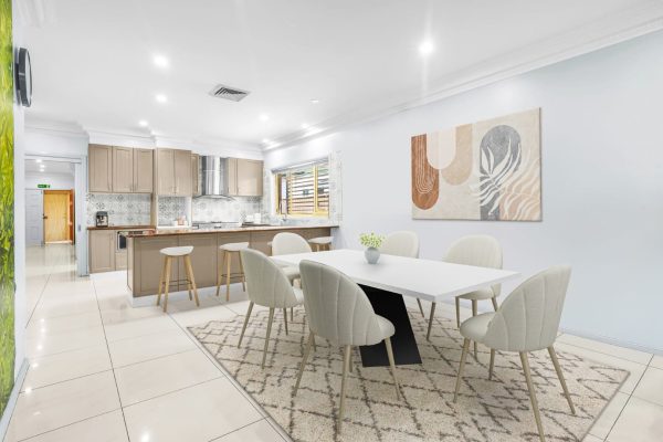 Fairfield 6 Modern kitchen and dining area with a white table, six chairs, a kitchen island with stools, neutral decor, and art on the wall.